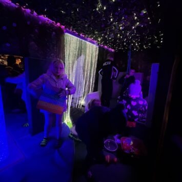 a dark image shows a blue bubble tube with children playing nearby