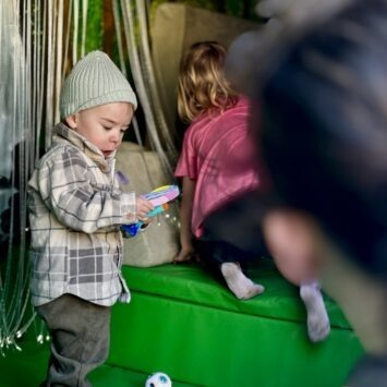 obscured by an adult, a young child fiddles with a heart shaped popper