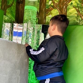 a young boy stares at the green bubble tube