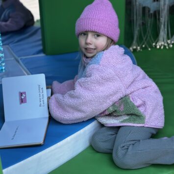 young girl reads book inside the sensory bus
